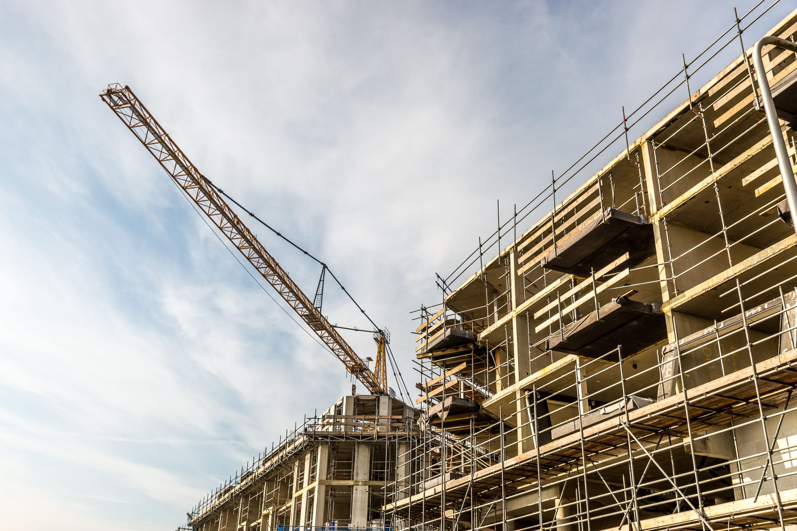 Home A dynamic view of a construction site with crane and scaffolding on a sunny day.